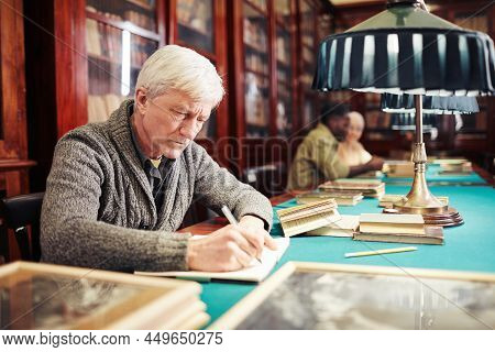 Portrait Of White Haired Senior Man Studying In Classic Library By Lamp Light, Copy Space
