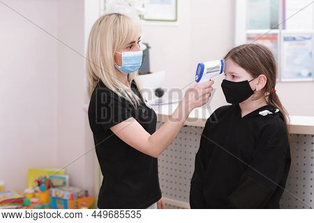 Female Doctor In Medical Mask With Contactless Infrared Themometer Gun Measuring Fever, Scanning For