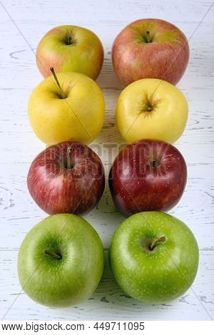 Six Multicolored Apples On A White Wooden Background