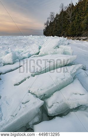 Sunset Light Colors The Sky Over Ice Patterns And Piles Of Ice Plates Called Ice Shoves On The Green