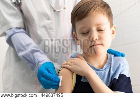 A Doctor In A White Medical Coat And Rubber Gloves With A Phonendoscope Makes A Coronavirus Vaccinat