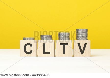 Wooden Cube On A Concrete Surface With Text Cltv. Copy Space On Right For Design, Yellow Background