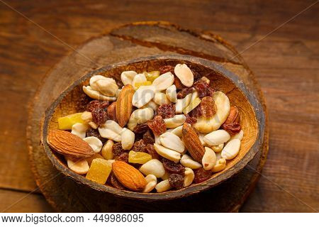 A Mixture Of Dried Fruits And Nuts In A Coconut Shell Plate On A Wooden Table. Horizontal Photo