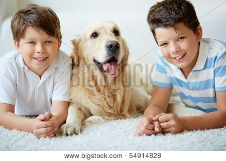 Portrait of happy siblings with their pet having rest at home
