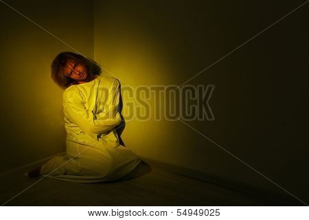 Mentally ill man in strait-jacket in room corner