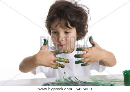 Kleine jongen kijkt zijn zeer vuile vingers met verf