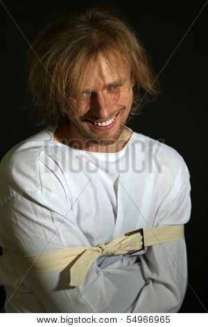 Mentally ill man in strait-jacket on black background