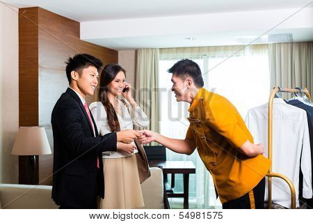 Baggage porter or bellboy or page receiving tip for delivering the suitcase of guests to the hotel room or suite