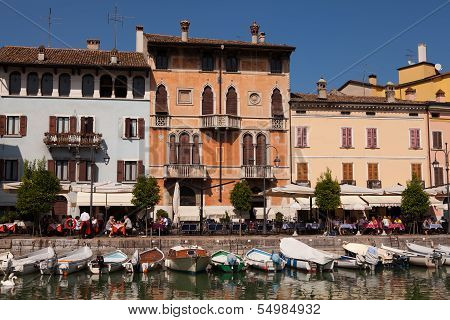 DESENZANO, ITALY - SEP 13 2013 : Customers relax by the harbour and boats rest at their moorings.