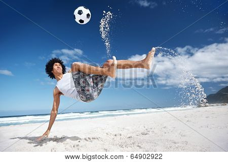 Latino Hispanic man doing bicycle kick on beach with soccer ball