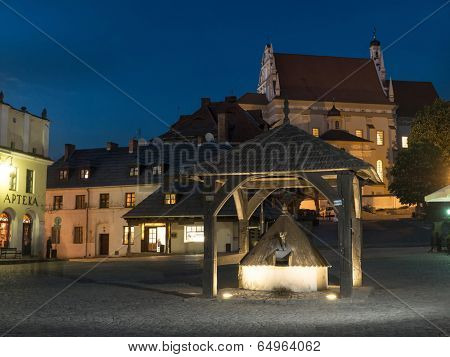 Kazimierz Dolny town square by night with historical wooden well in the center, Poland