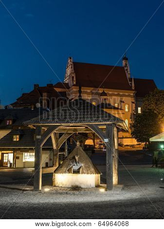 Kazimierz Dolny town square by night with historical wooden well in the center, Poland