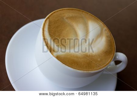 Cup of art latte on a cappuccino coffee on table.