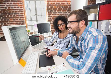 Side view of two photo editors using digitizer in the office