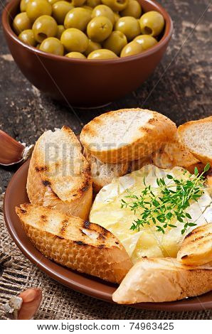 Baked Camembert cheese with thyme and toast rubbed with garlic