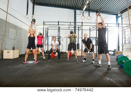 Group of young male and female athletes lifting kettlebells 