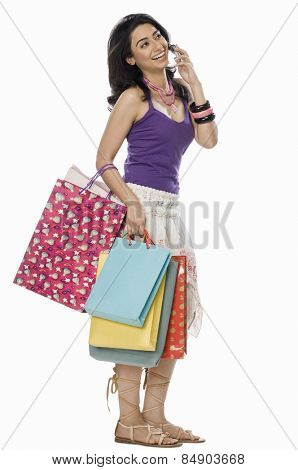 Woman carrying shopping bags and talking on mobile phone