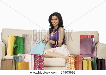 Portrait of a woman sitting on a sofa and holding shopping bag