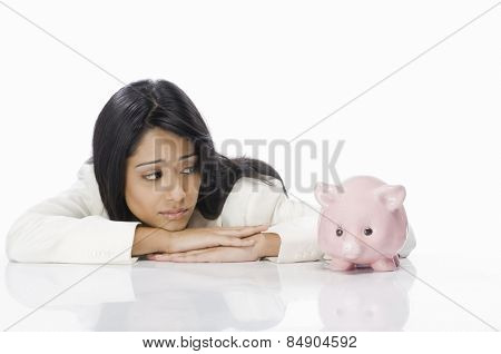 Businesswoman looking at a piggy bank