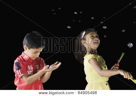 Girl blowing bubbles and a boy looking at his palm