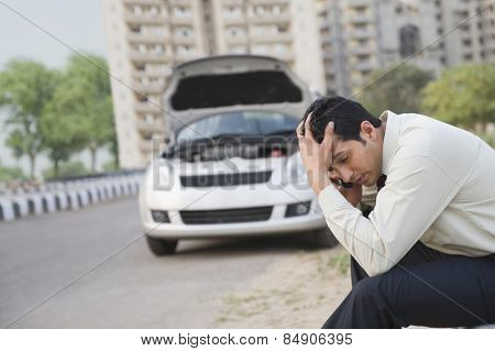 Worried businessman talking on a mobile phone after his vehicle breakdown