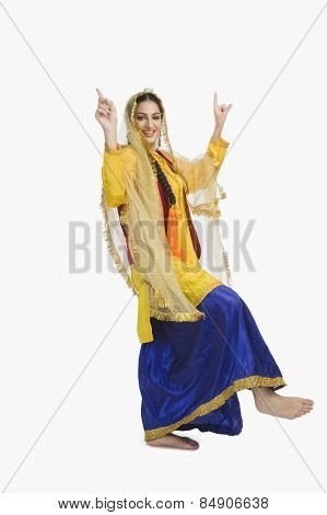 Woman in traditional yellow Punjabi dress doing bhangra