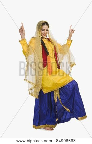 Woman in traditional yellow Punjabi dress doing bhangra