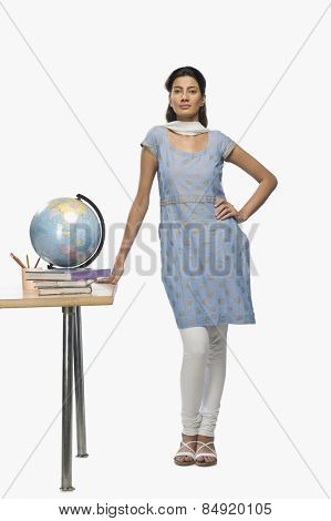 Female teacher standing beside a desk