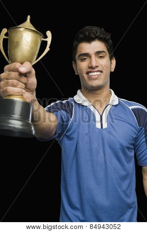 Soccer player holding a trophy and smiling