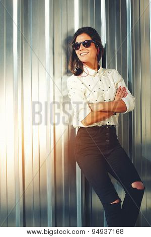 Portrait of attractive brunette hipster woman posing on shiny wall background in sunglases