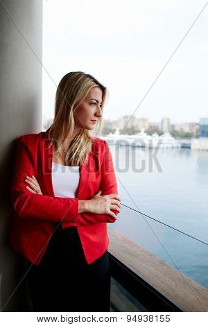 Young female executive with crossed arms thoughtfully looking away while having work break