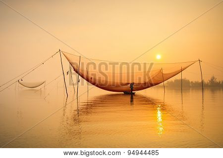 Unidentified fisher man check his nets in early morning on river in Hoian, Vietnam.