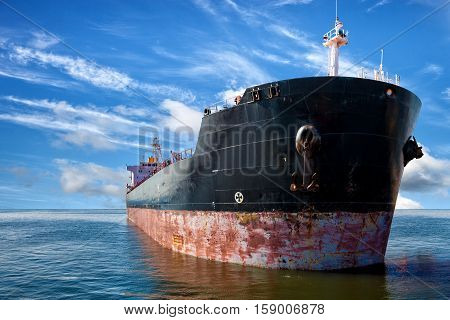 Oil tanker ship at sea on a background of blue sky.