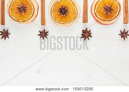 Christmas food - mulled wine background. Decorative frame of spice ingredients - anise stars cinnamon dried oranges and wine on wood white surface. Top view.