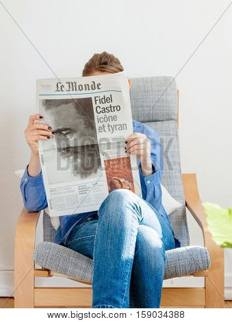 PARIS FRANCE - NOV 29 2016: Woman reading Le Monde newspaper with headline and articles about Fidel Castro Cuban President - dead on November 25 2016