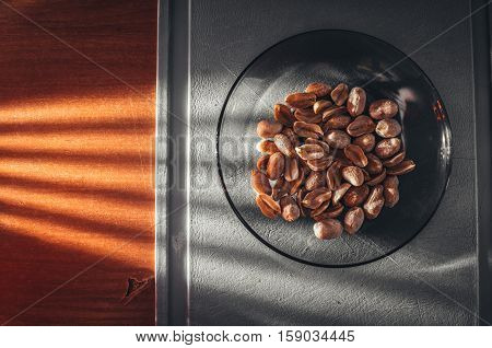 Roasted salted peanuts in a plate on old wooden table, on Board
