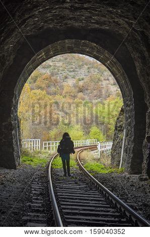 Railway stone tunnel and woman inside autumn day
