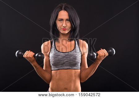 Sports and bodybuilding concepts. Fitness woman posing with dumbbells in both hands while posing for photographer isolated on black in studio.