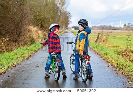 Two active kids boys in helmet biking on bicycles. Happy children in colorful clothes and city traffic. Safety and protection for preschool kids. Friends making sports, acitve leisure.