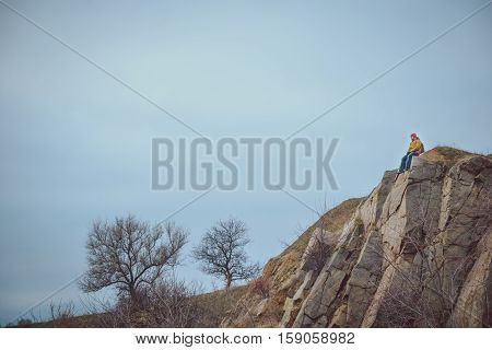 lonly man on a cliff in clod autumn wather
