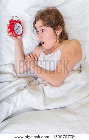 Young Woman Is Waking Up And Looking At Clock. She Oversleep And