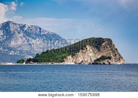 Stone Island With Green Forest At Sea Near High Mountain