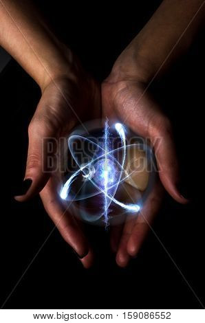 Female hands hold crystal ball with atom particle for fortune telling background