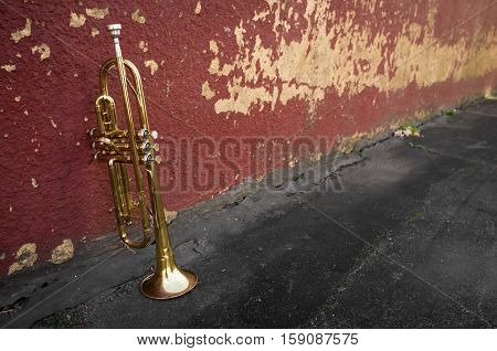 Old worn trumpet stands alone against a grungy pealing brick wall
