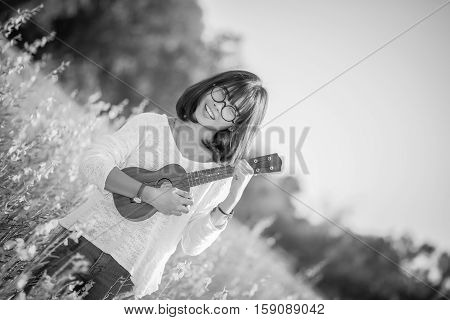 .young Woman Playing On Ukulele On Sunhemp Background