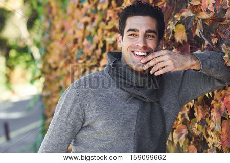 Man Wearing Winter Clothes Smiling In Autumn Leaves Background