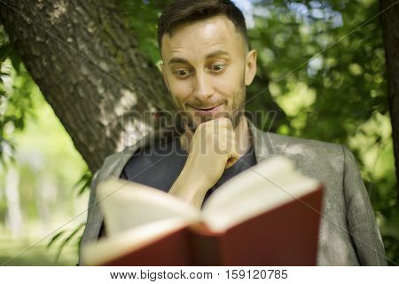middle aged man rading book in park