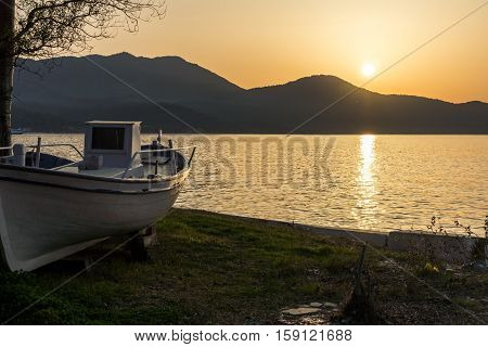Sunset seascape with old boat on embankment of Thassos town, East Macedonia and Thrace, Greece