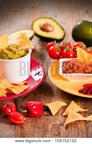 Guacamole and nacho chips on wooden table.
