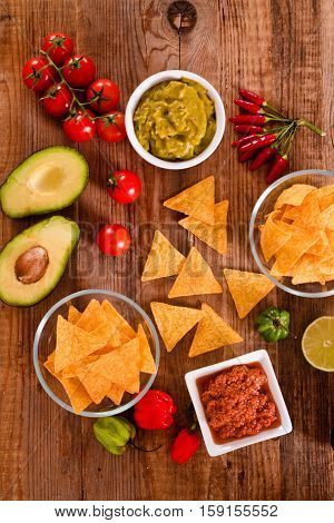 Guacamole and nacho chips on white bowl.